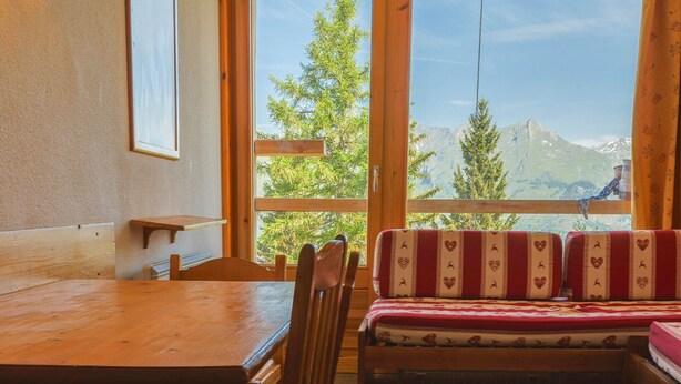 A wooden interior with a table, chairs, and a bench with patterned cushions. - Ski-in/ski-out studio, balcony, pets allowed, Arc 1800 (Les Arcs 1800)