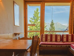 Ein Holzinterieur mit Tisch, Stühlen und einer Bank mit gemusterten Kissen.