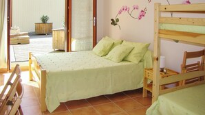 Een slaapkamer met een bed, een houten stoel, een nachtkastje en een raam met uitzicht.