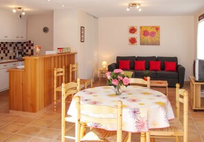 A compact living space with a dining area, a kitchen, and a sofa.