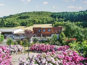 A building with a balcony and a garden with pink flowers.