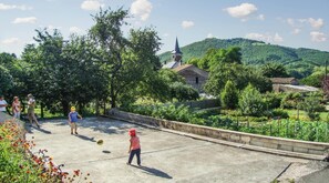 Ein Innenhof mit einem Volleyballnetz, umgeben von Bäumen und einer Kirche im Hintergrund.