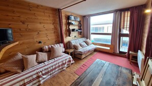 A cozy cabin-style room with wooden walls, a sofa, a small table, and a television. - 2-room apt for 5 in Villards, Arc 1800, pets allowed (Les Arcs 1800)
