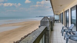 Un balcone con vista sulla spiaggia, caratterizzato da un pavimento piastrellato e diverse sedie.