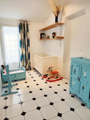 Quarto com berço, cavalinho de balanço e um armário azul.