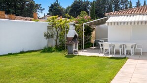 A backyard with a grill, white chairs, and a patio table. - Homerez - Villa in Meynes (Meynes)