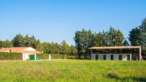A building with a green door, a white door, and a small structure with a green roof. - Homerez - Villa in Meynes (Meynes)
