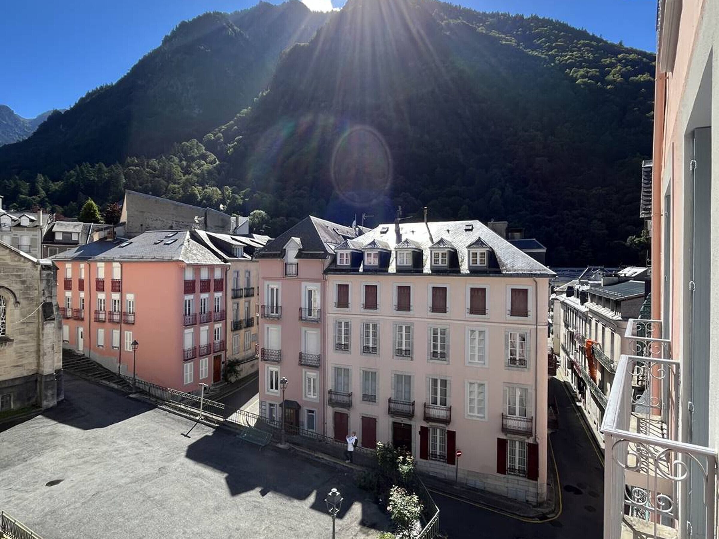Une vue de rue avec des bâtiments, un ciel dégagé et une montagne en arrière-plan.