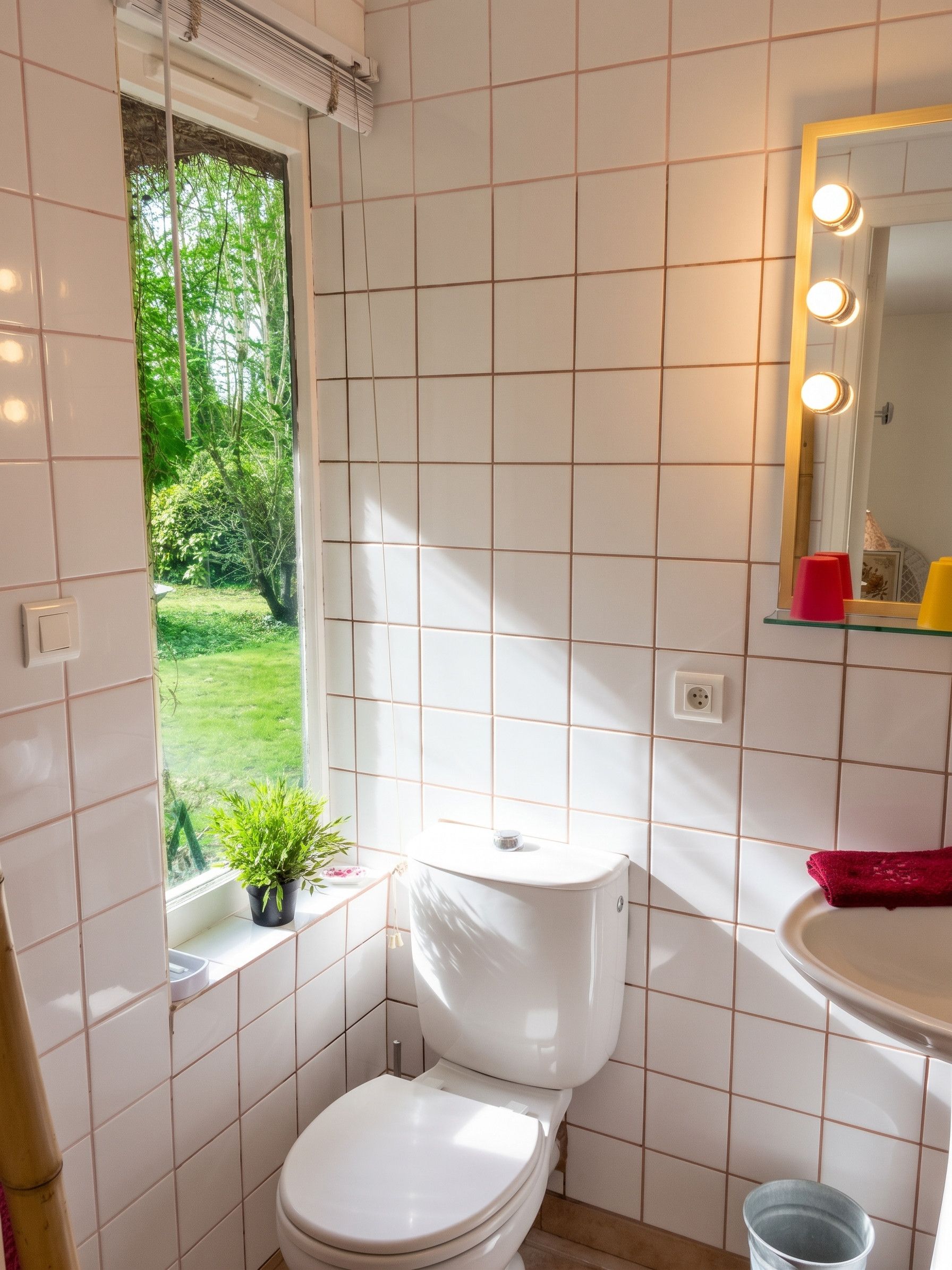 Une petite salle de bain comprenant des toilettes, un lavabo et une fenêtre.