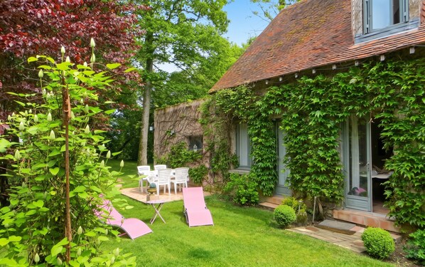 A garden with a dining area, a pergola, and a house with a tiled roof. - Homerez - House in Saint Branchs (Saint Branchs)