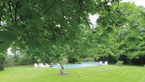 A well-maintained lawn with a small tree and a pool in the background. - Homerez - House in Saint Branchs (Saint Branchs)