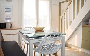 Une cuisine moderne avec une table à manger en verre, des chaises blanches et un escalier.