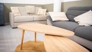 A living room with a grey sofa, a beige sofa, a wooden coffee table, and a woven rug. - Homerez - House in Saint-Cyprien (Saint-Cyprien Plage)