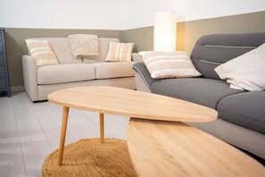 Un salon avec deux canapés, une table ronde en bois et une lampe.