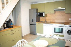 A compact kitchen with a refrigerator, microwave, oven, and washing machine.