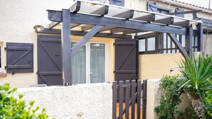 A house with a covered patio, a gated entrance, and a white exterior wall. - Homerez - House in Saint-Cyprien (Saint-Cyprien Plage)