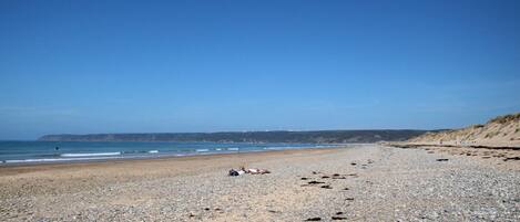 A pebbly beach with a clear sky and calm sea.