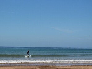 A beach scene with a person surfing. - Charming Beachside House: Terrace, Pet-Friendly, Near GR223, with Wifi & Baby Equipment (La Hague)
