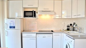 A modern kitchen with white cabinetry, a microwave, a dishwasher, and a washing machine. - Modern Apartment, 2 Bedrooms, Terrace, A/C, Parking, Near Beach, Cavalaire (Cavalaire-sur-Mer)