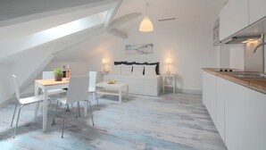 Um apartamento estilo loft moderno com área de jantar, cozinha e espaço para dormir.