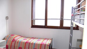 A dormitory room with bunk beds, a window with blinds, and a desk with a chair. - Charming Ski-In Apartment, Sleeps 6, South-Facing Balcony, Ideal for Families - Peyragudes (Gouaux-de-Larboust-Les Agudes)