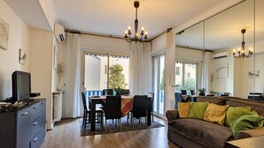 A modern living room with a sofa, a dining table, and a TV. - N&J - L'OLYMPIC - Central - Very close sea (Niza)