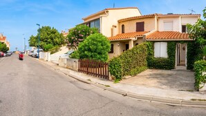 A residential street with houses, parked cars, and a clear sky.