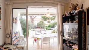 A room with a bed, a dining table, chairs, a sofa, a sliding glass door to an outdoor area, and a built-in bookshelf.