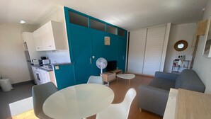 A compact living space with a kitchenette, a dining area with a table and chairs, a sofa, and a television. - Charming 1-Bed Apt with South-Facing Terrace, Beach Access & Parking in Arcachon (Arcachon)