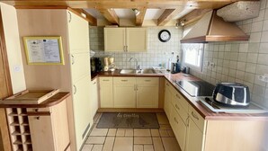 Una cocina compacta con vigas de madera, un lavamanos, un tostador y un reloj en la pared.