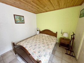 Une chambre à coucher avec un lit en bois, une table de chevet avec une lampe, un mur vert et un tableau encadré.