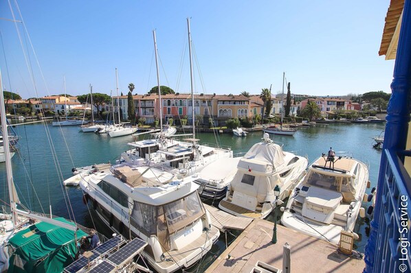 Un port de plaisance où sont amarrés différents types de bateaux, entouré de bâtiments à l’architecture méditerranéenne.