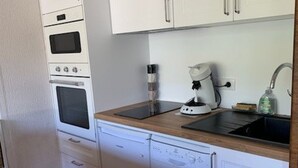 A compact kitchen with a built-in oven, a coffee machine, and a dishwasher.