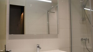 A modern bathroom with a white sink, a mirror, and a glass shower enclosure.