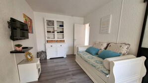 Ein gemütlicher Wohnbereich mit einer Couch, einem Schrank, einem Fernseher und einer kleinen Pflanze.