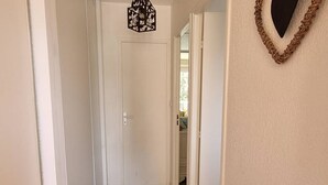 Ein schmaler Korridor mit Holzboden und weißen Wänden.