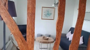 Una sala de estar con una mesa de centro redonda de madera, un sofá y un cuadro enmarcado en la pared.
