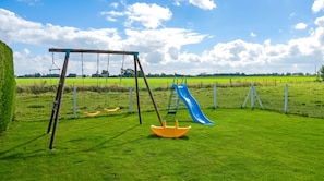 Ein Spielplatz mit Schaukeln und einer Rutsche.