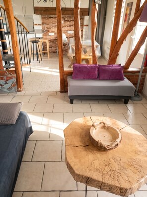 Un salon moderne avec un canapé, une table basse et, au fond, un coin repas.