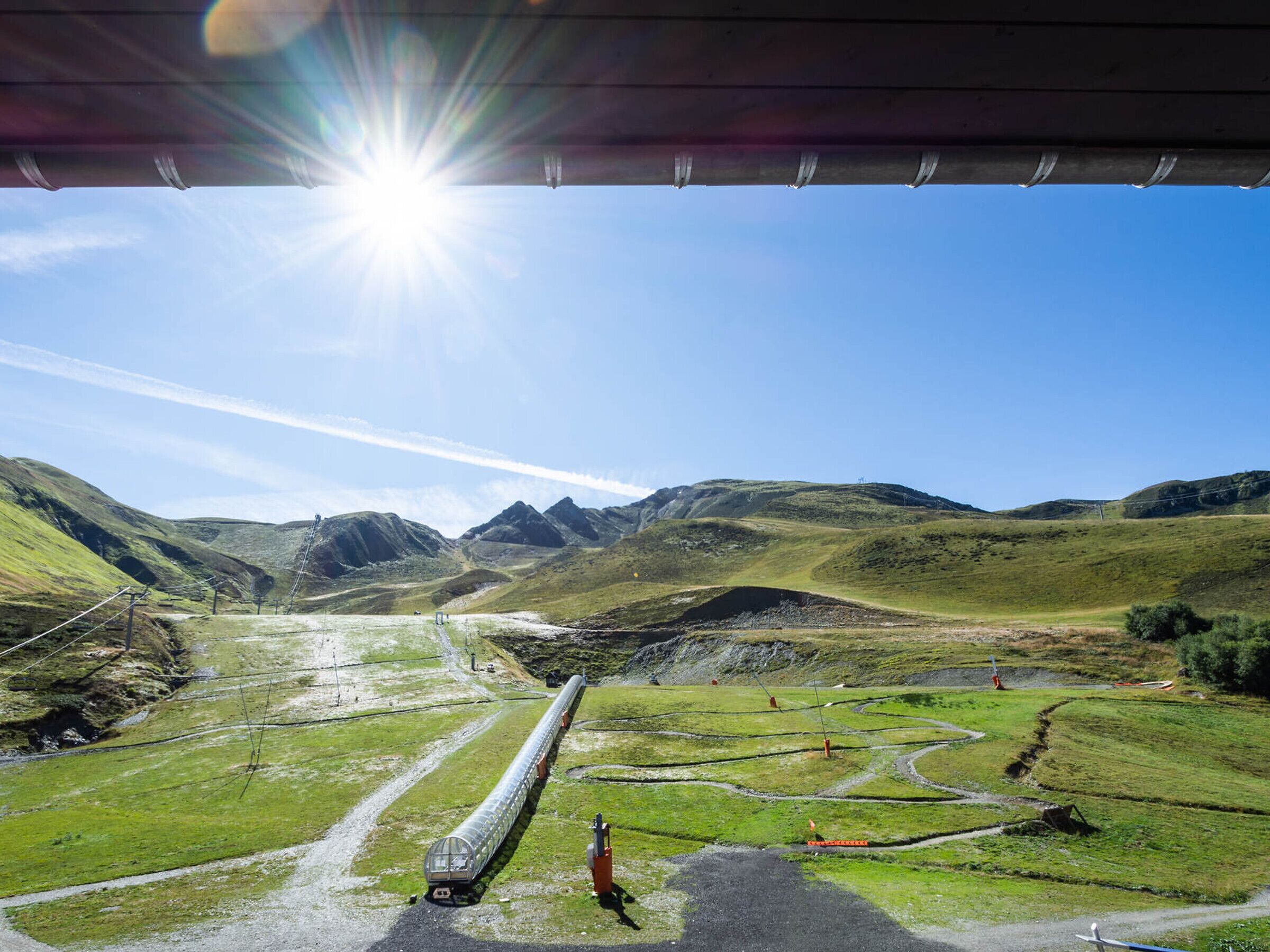 Un train circule sur une voie ferrée, avec un paysage montagneux en arrière-plan.