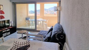 Een balkon met uitzicht op een stadsbeeld, een bank, een televisie en een eettafel met stoelen.