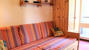 A wooden bench with a striped cushion and a pillow with a floral pattern. - Cozy 2-Room Mountain Apartment for 5 in the Heart of Vars, Near Slopes and Shops (Vars)