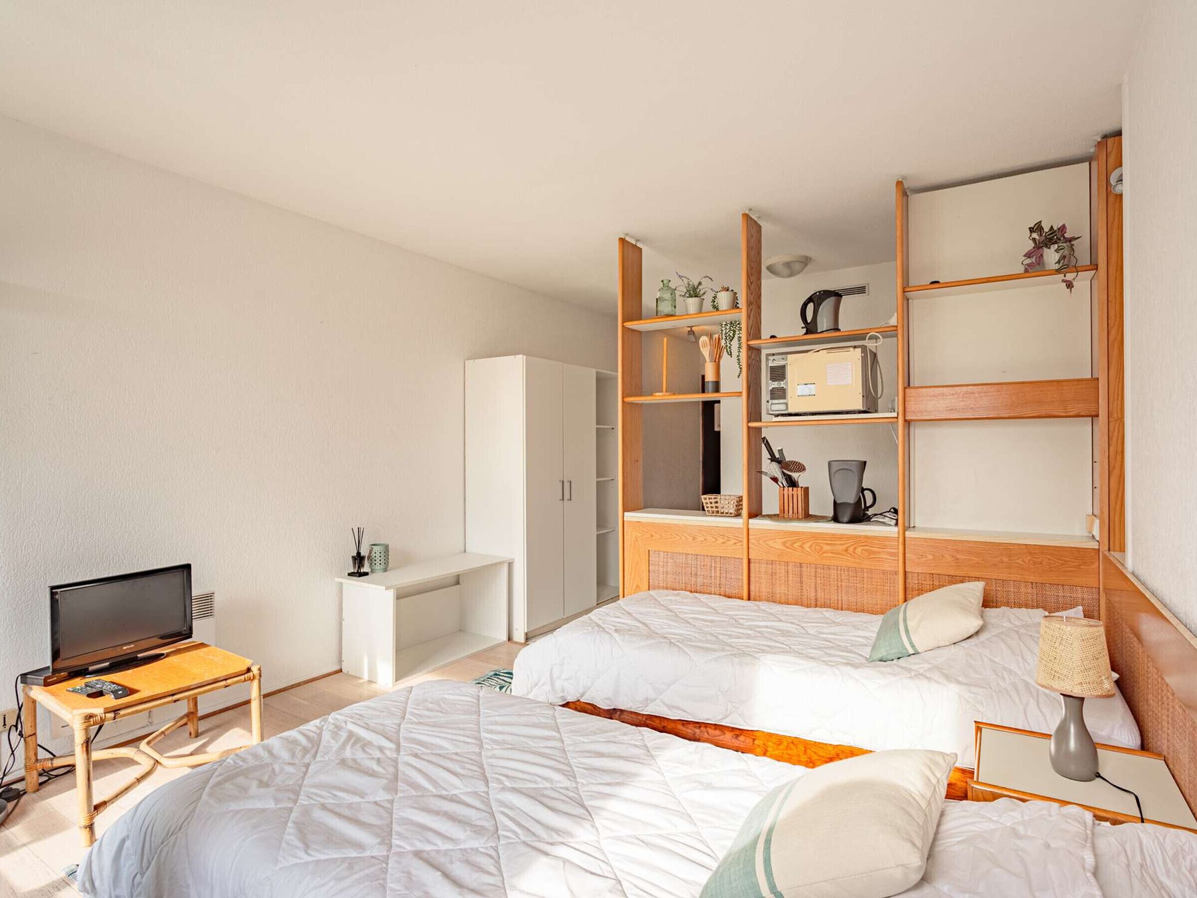A hotel room with two beds, a TV, a desk, and a wardrobe.