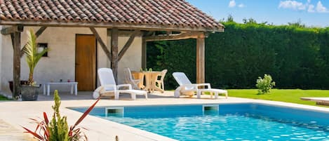 A swimming pool with lounge chairs and a pergola.