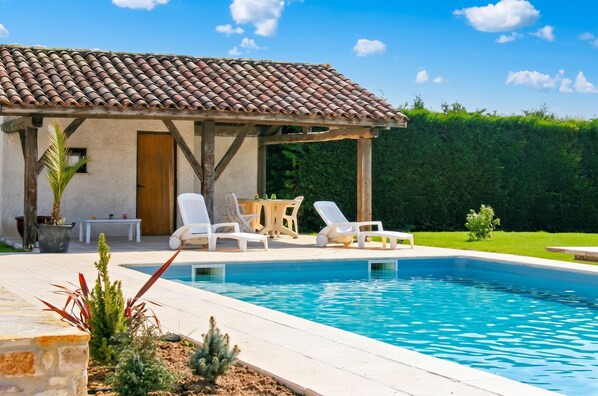 A swimming pool with lounge chairs and a pergola.