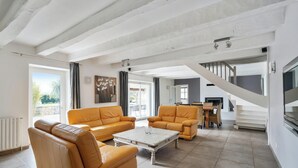 A spacious living room with a high ceiling, a staircase, and a dining area.