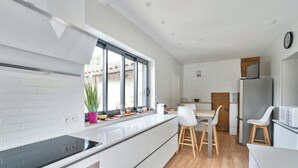 A modern kitchen with a large island, white cabinetry, and a built-in stove.