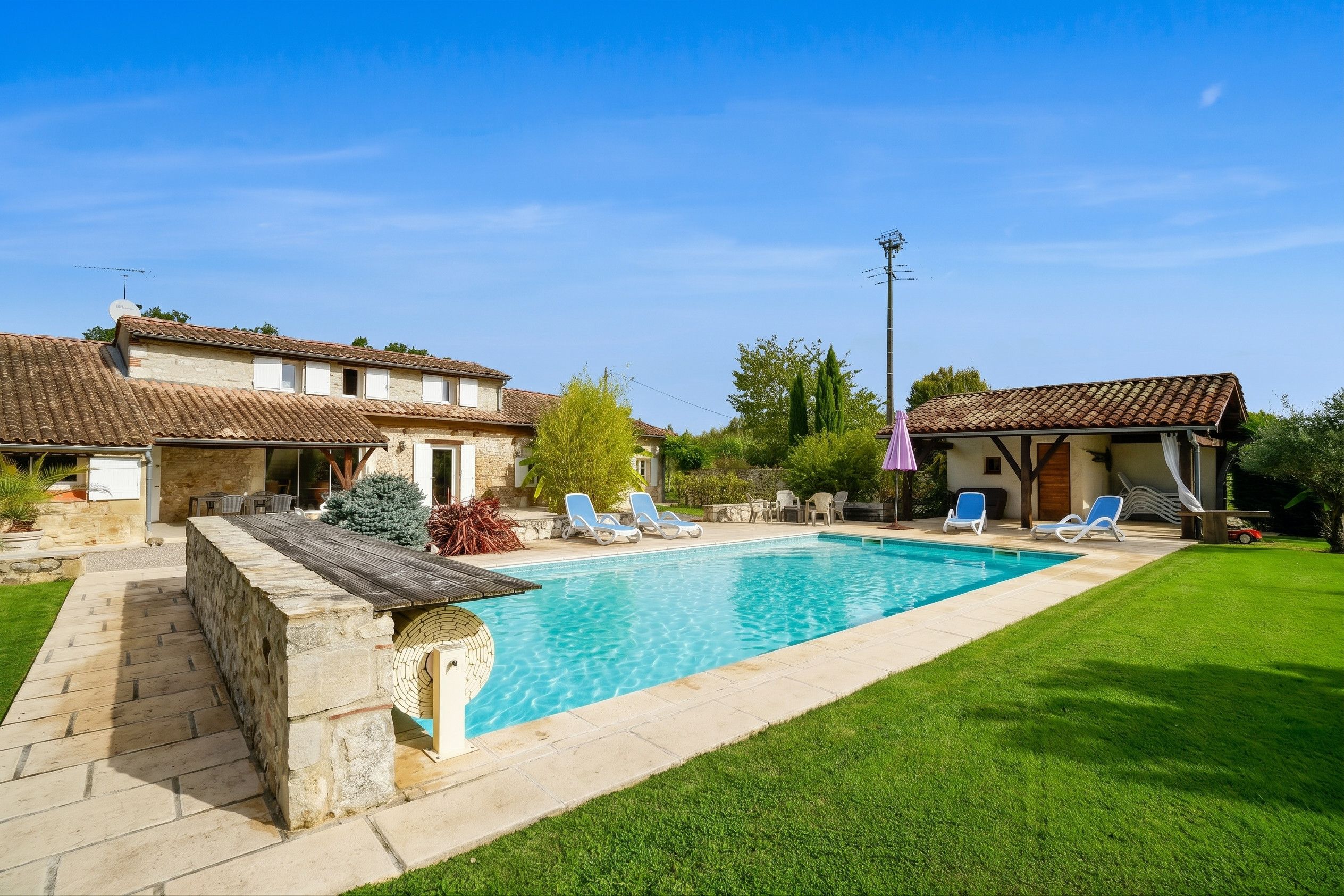 Propiedad residencial con piscina, mobiliario exterior y césped cuidado.