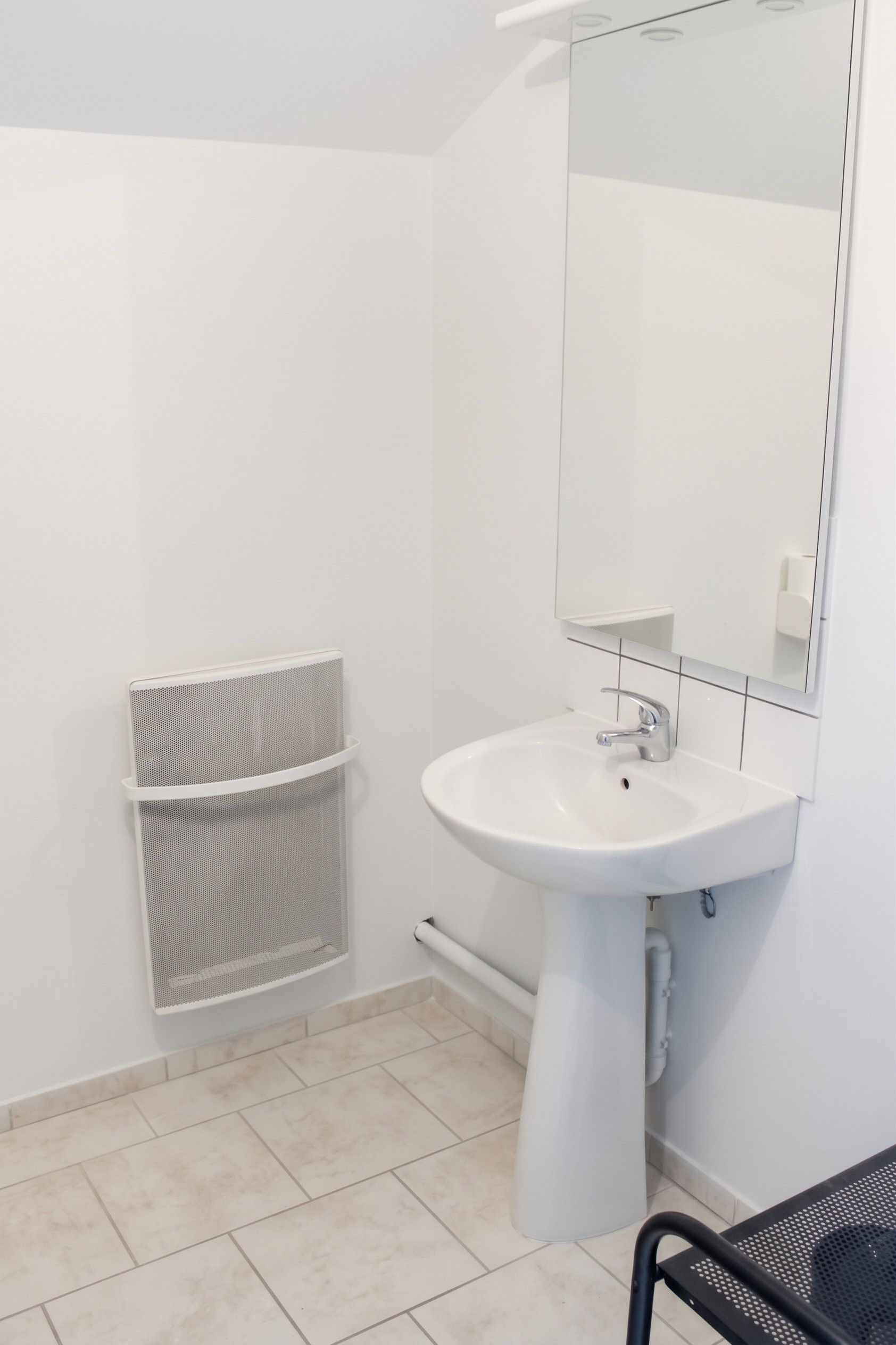 A bathroom with a white sink, a mirror, and a towel rack.