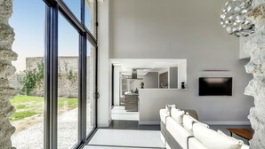 Ein modernes Wohnzimmer mit großem Fenster, einer Couch und einem Fernseher an der Wand.